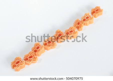 A line of orange pasta spiders crawling diagonally
