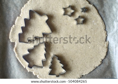 Christmas cookie cutters on the raw dough on the parchment top view