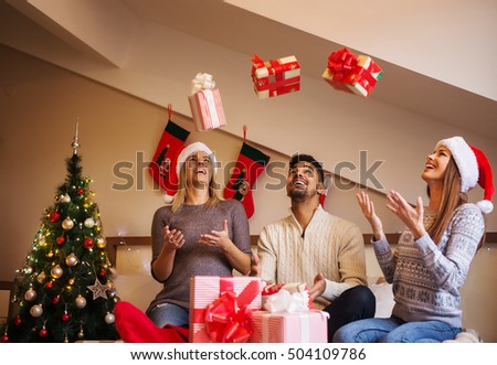 Cheerful friends throwing their Christmas gifts in the air.