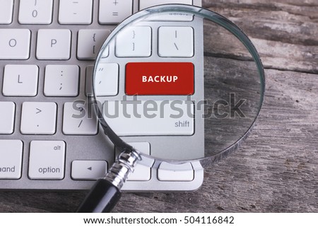 Business concept: BACKUP on computer keyboard on wooden background with copyspace area