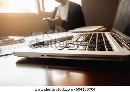 Asian business woman manager analyzing datum in charts and typing on computer, making notes in documents on the table in office, vintage color, selective focus. Business concept.


