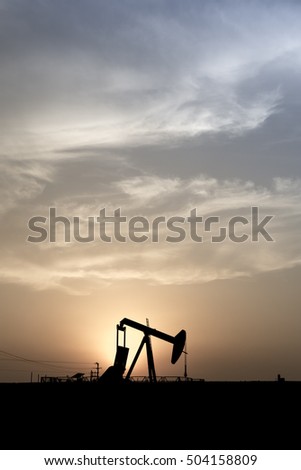 Silhouette of crude oil pump at sunset in oil field.