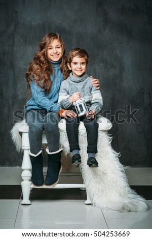 Portrait of two beautiful kids dressed in sweaters and jeans on vintage background. Cozy fashion look for kids on christmas or autumn time. Fashion and beauty concept. Family, brother and sister.