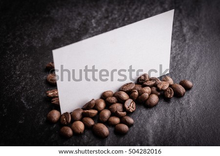 roasted coffee beans with blank paper on dark background, can be used as a background