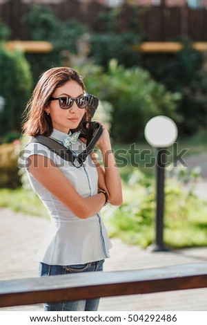 Happy young woman in sunglasses holds modern digital photo camera