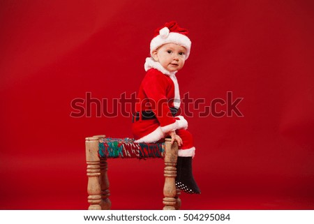 cute kid in Santa Claus clothes. sitting on a chair
