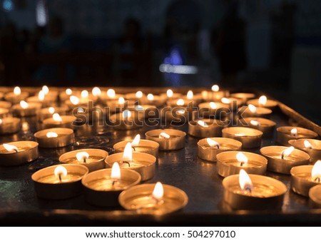 lit votive candles in church on black background