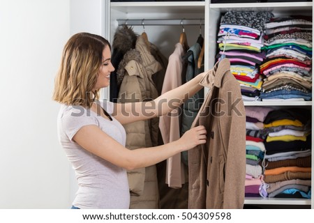 Young woman is standing in front of her closet trying to find perfect outfit.