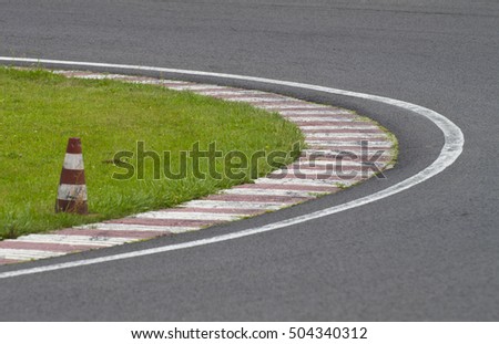 sleek asphalt and danger at the bend of the motorbike track and red orange striped cones, motoGP