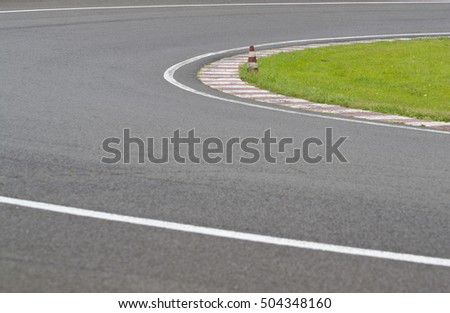sleek asphalt and danger at the bend of the motorbike track and red orange striped cones, motoGP