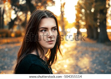 Girl brunette with brown eyes on the background of autumn