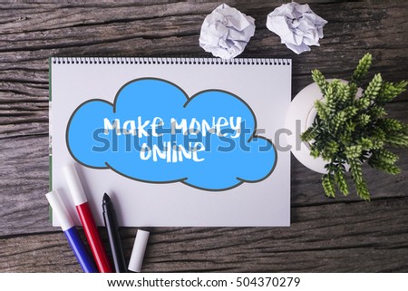 Notepad and green plant on wooden background with make money online word
