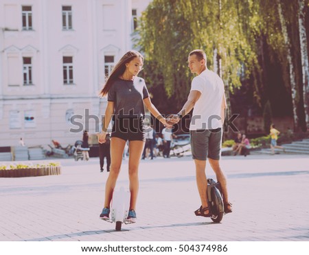 Young couple driving on segway in the park.