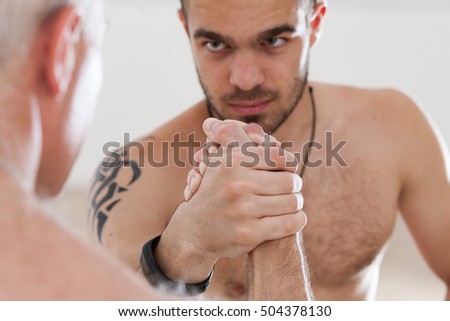 arm wrestling young VS mature with apprentice staring at his master trying to look stronger