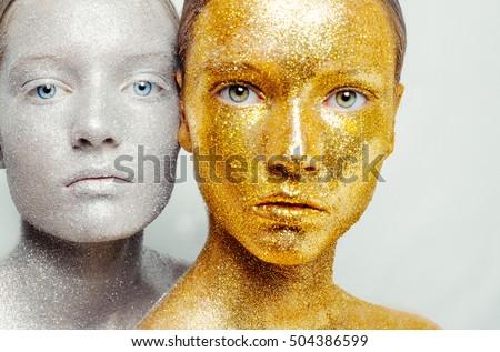Beautiful, amazing portrait of two woman. Unreal make up like a space. Closeup shooting in studio with silver background. Emotion, posing of model. gold silver glitter.