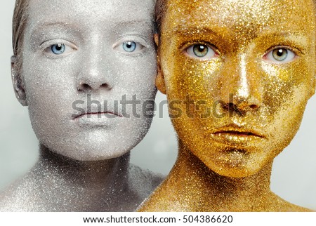 Beautiful, amazing portrait of two woman. Unreal make up like a space. Closeup shooting in studio with silver background. Emotion, posing of model. gold silver glitter.