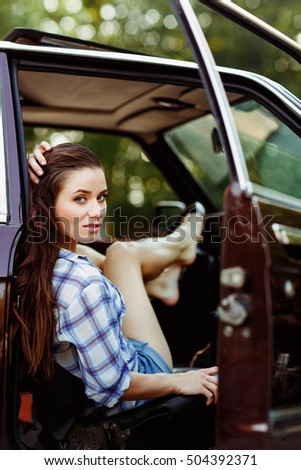 Serious brunette in burgundy car , tinted photo