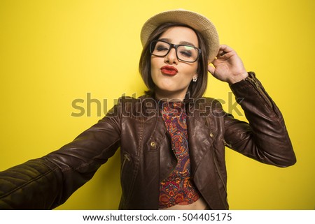 Portrait of a Beautiful successful smiling girl doing selfie  on a yellow background