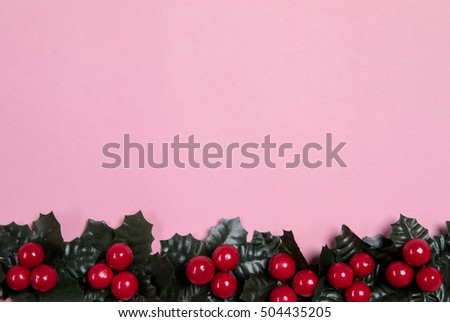 Holly berry frame over pink background.
