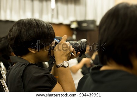 Woman taking picture in workshop room with hand holding a pen