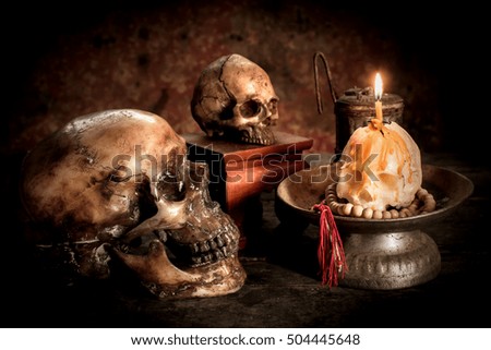 Skull and candle with candlestick on wooden background, still life concept