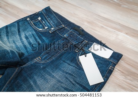 Blue jeans with price tag on  wooden background