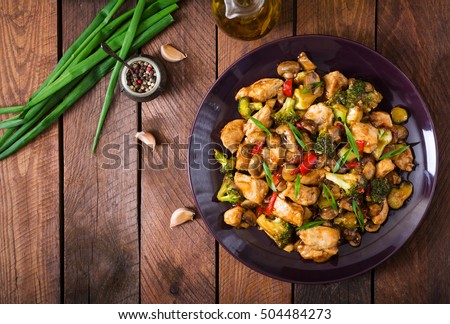 Stir fry with chicken, mushrooms, broccoli and peppers - Chinese food. Top view Royalty-Free Stock Photo #504484273