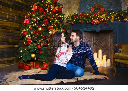 Young couple near fireplace celebrating Christmas. Love and relationship concept.