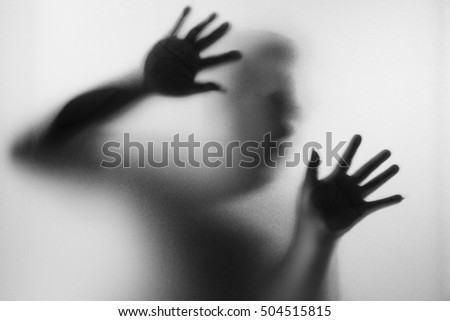 Horror man behind the matte glass in black and white. Blurry hand and body figure abstraction.Halloween background.Black and white picture