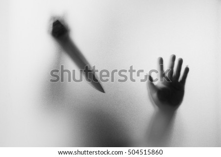 Horror Murderer. Dangerous man behind the frosted glass with a knife on his hand.Halloween background.Black and white picture Royalty-Free Stock Photo #504515860
