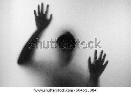 Horror woman behind the matte glass in black and white. Blurry hand and body figure abstraction.Halloween background.Black and white picture
