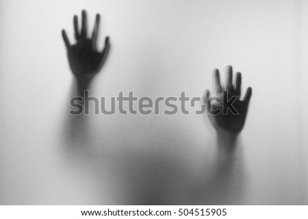 Shadow hands of the Man behind frosted glass.Blurry hand abstraction.Halloween background.Black and white picture Royalty-Free Stock Photo #504515905