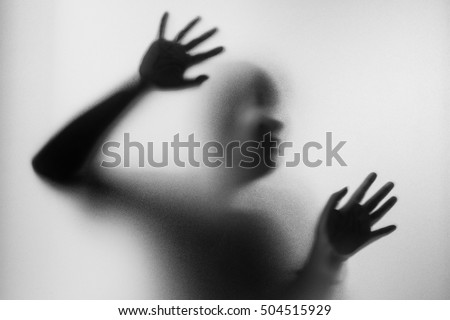 Horror woman behind the matte glass in black and white. Blurry hand and body figure abstraction.Halloween background.Black and white picture