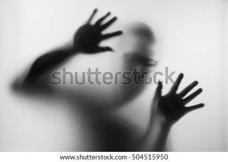Horror man behind the matte glass in black and white. Blurry hand and body figure abstraction.Halloween background.Black and white picture