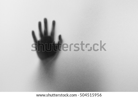 Shadow hands of the Man behind frosted glass.Blurry hand abstraction.Halloween background.Black and white picture Royalty-Free Stock Photo #504515956