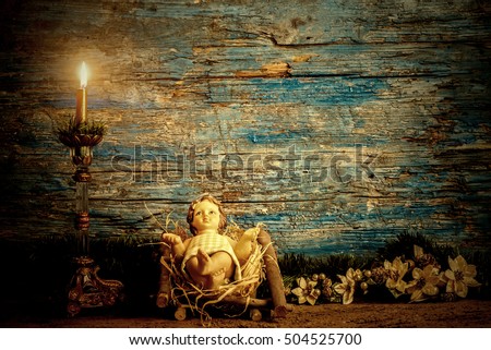Christmas greeting card, baby Jesus in his crib and vintage candle, rustic wooden background with copy space for text Royalty-Free Stock Photo #504525700