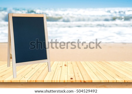 Blank blackboard sign and wood deck on the beach and blue sky,Ready for products.