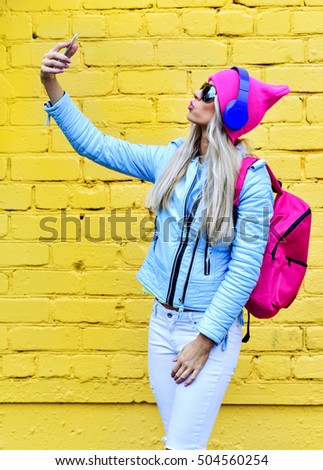 Fashion woman makes self portrait on smartphone over city  colorful yellow background
