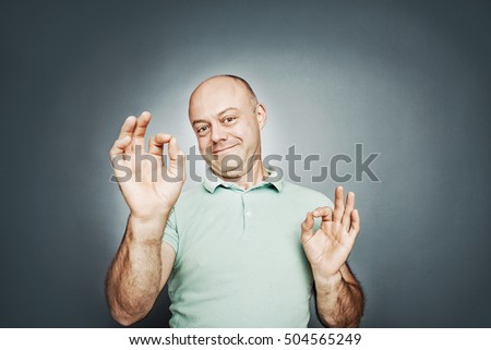 middle-aged man of average shows a sign ok hands. on a gray background