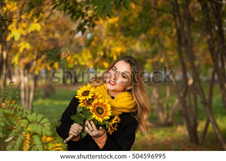 Beautiful girl with sunflowers in the autumn rowan