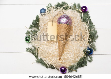 Colorful Christmas or New Year decoration with violet silver christmas ball, ice cream cone, yellow tag and tree branch with balls on vintage white background