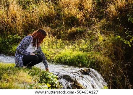Young lady and a small river in autumn colors