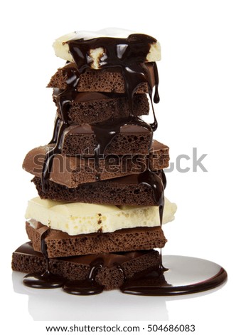 A stack of slices of porous black and white chocolate sprinkled with hot chocolate isolated on white background.