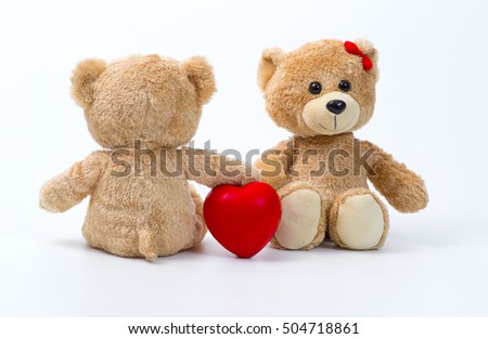 Teddy bear holding a heart-shaped pillow with 