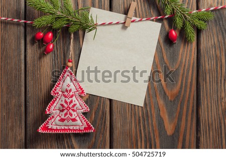 Christmas decorations hanging with blank sheet of paper on rope on wooden background.