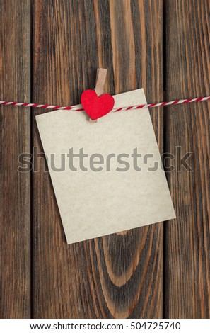 Paper sheet with heart hanging on rope on wooden background. Valentines day card.