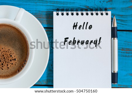 Hello february - inspiration in notepad near cup of morning coffee at workplace or ather blue table. Top view, winter time