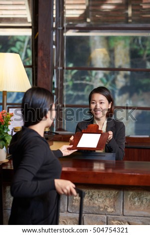 Receptionist giving document to the guest to sign