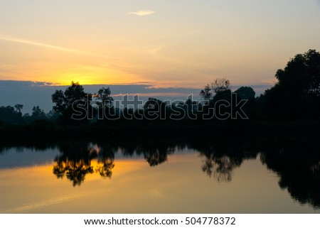 Silhouette of trees with reflection in the water in sunset