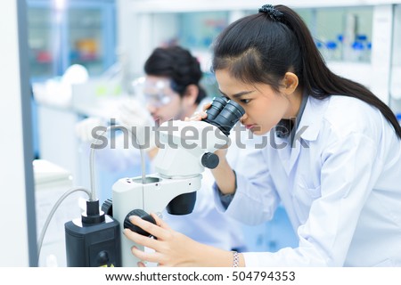 group of scientists working at the laboratory .she use microscope Royalty-Free Stock Photo #504794353